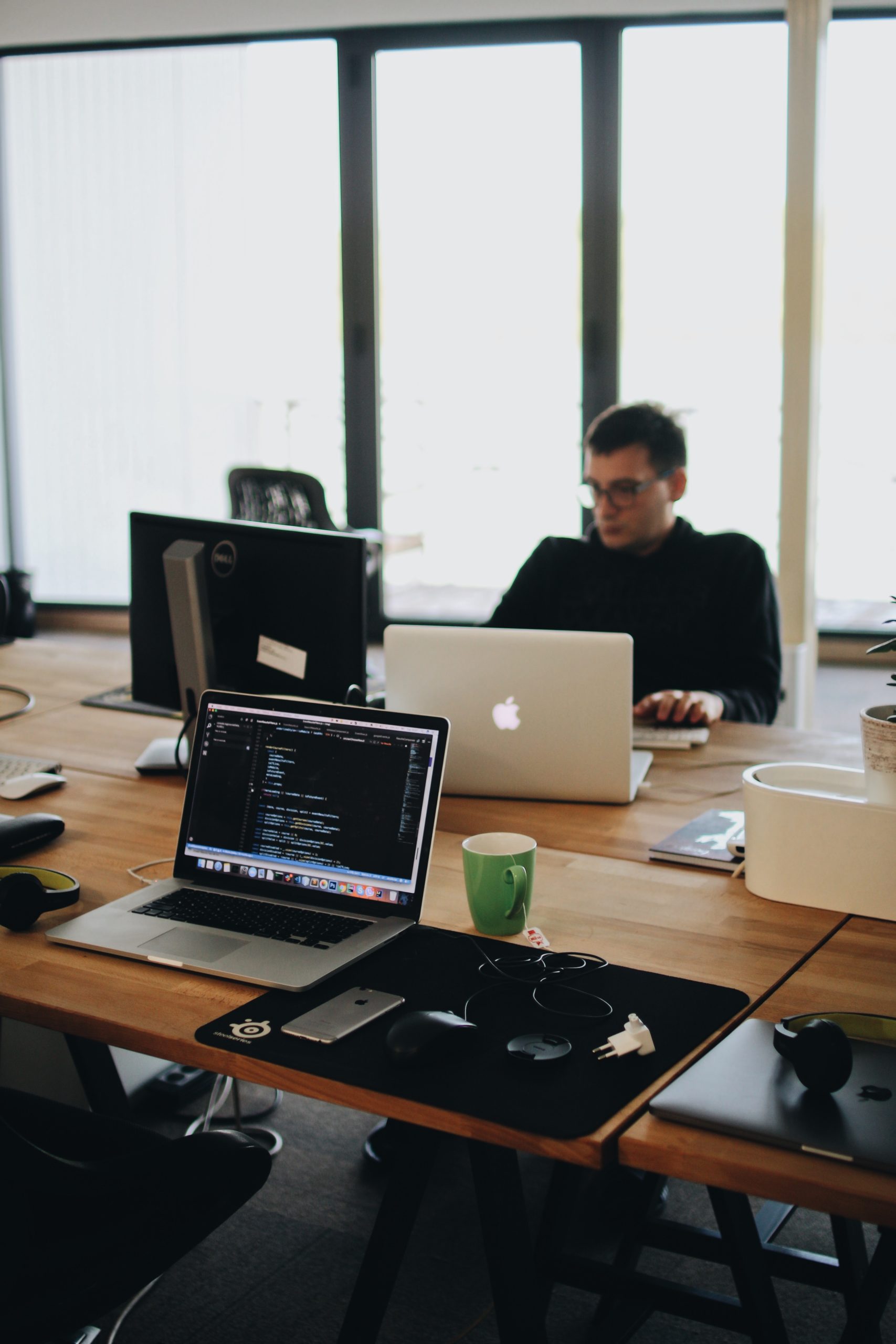 A man sitting at a desk wondering whether he needs a web designer or a web developer or both
